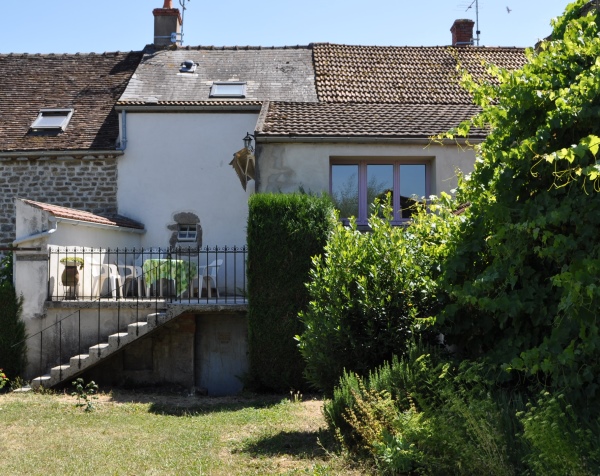 une vue de l'arrière du gîte, avec la terrasse depuis le jardin